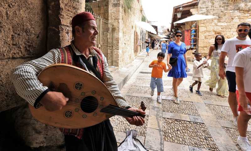 A busker performs as tourists walk by in Byblos, Lebanon, July 29, 2023. Photo: Xinhua