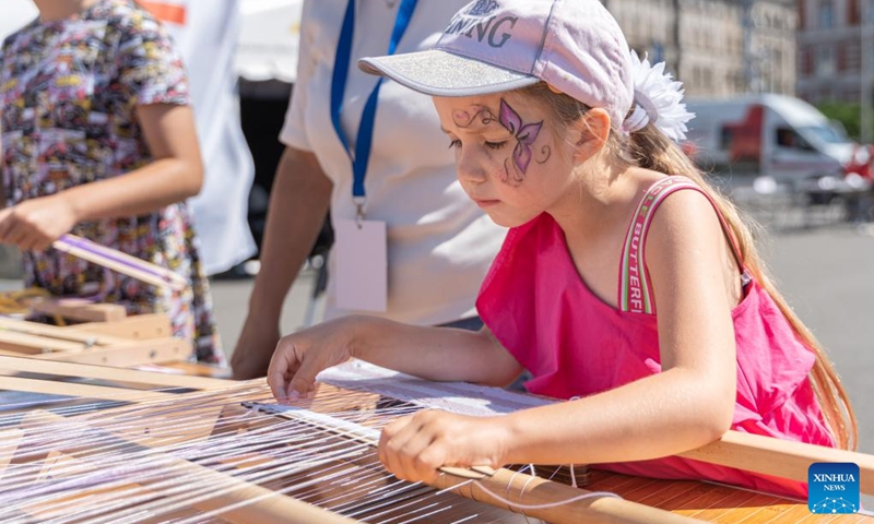 A girl learns to weave during a Knowledge Day event to celebrate the start of the new school year on the central square of Vladivostok, Russia, Sept. 2, 2023. Programs like popular sciences, painting, dictation, handicraft, fire safety knowledge and other activities on Knowledge Day attracted many children. Photo: Xinhua