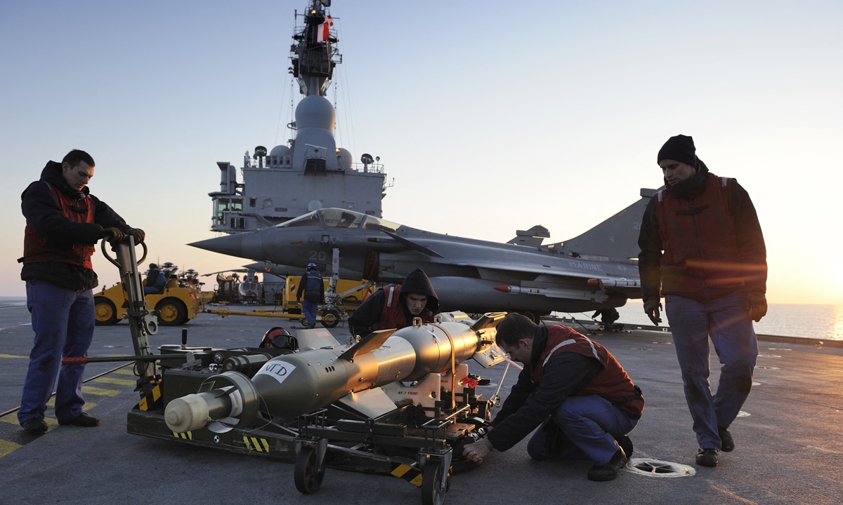 French navy technicians prepare a BGU 12 bomb to be attached onto a Rafale jet fighter on the French aircraft carrier Charles De Gaulle, on March 25, 2011, for a mission to Libya. Photo: AFP