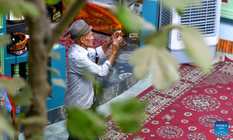 A tourist takes photos at the ancient city of Kashgar scenic area in Kashgar, northwest China's Xinjiang Uygur Autonomous Region, Sept. 7, 2023. The ancient city of Kashgar, located in southwestern Xinjiang, is the largest complex of raw earth buildings still in use in the world. (Xinhua/Wang Fei)