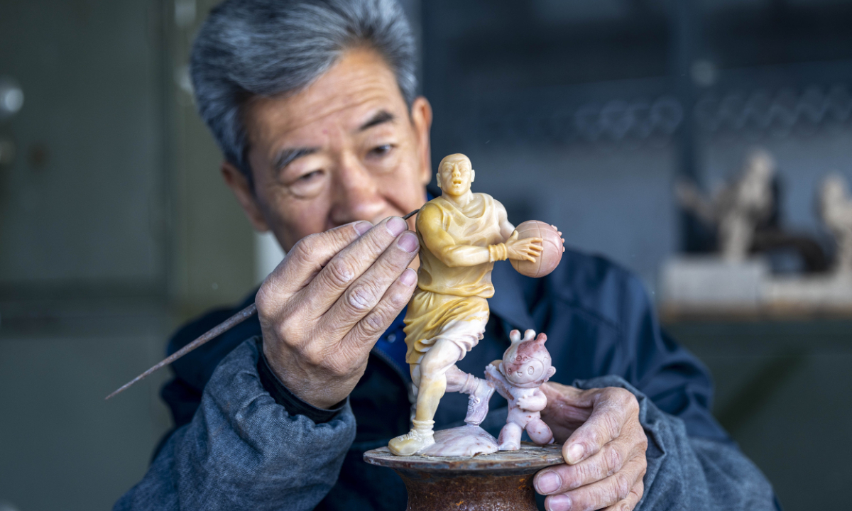 Qian Gaochao, an inheritor of China's intangible cultural heritage of Jixue stone carving, works on an Asian Games themed stone sculpture in Hangzhou, East China's Zhejiang Province, on February 22, 2023. Photo: CFP