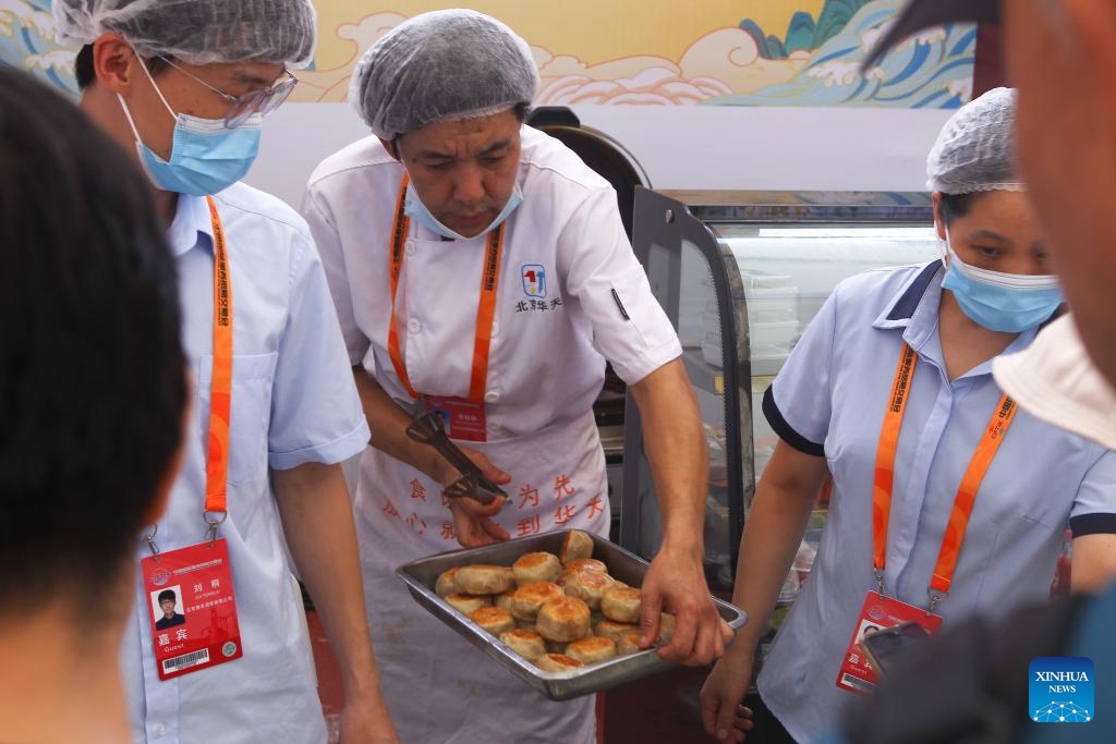 Staff members serve freshly baked meat pies at the exhibition hall of Beijing time-honored brand during the 2023 China International Fair for Trade in Services (CIFTIS) in Beijing, capital of China, Sept. 6, 2023. A number of time-honored brands in catering business made their debut at the exhibition hall of Beijing time-honored brand during the 2023 CIFTIS, attracting numerous guests to come for a taste.(Photo: Xinhua)