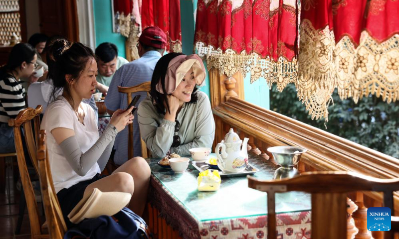 Tourists enjoy tea at a teahouse at the ancient city of Kashgar scenic area in Kashgar, northwest China's Xinjiang Uygur Autonomous Region, Sept. 7, 2023. The ancient city of Kashgar, located in southwestern Xinjiang, is the largest complex of raw earth buildings still in use in the world. (Xinhua/Lan Hongguang)