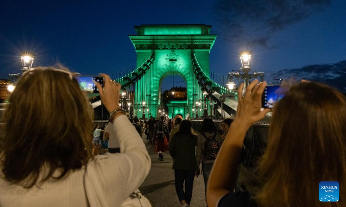 People enjoy the night view by Budapest's landmark Chain Bridge during the Chain Bridge Festival celebrating Budapest's 150th birthday in Budapest, Hungary on Sept. 16, 2023. In 1873, Buda, Pest and Obuda were unified into one single city, naming the city Budapest. (Photo by Attila Volgyi/Xinhua)

