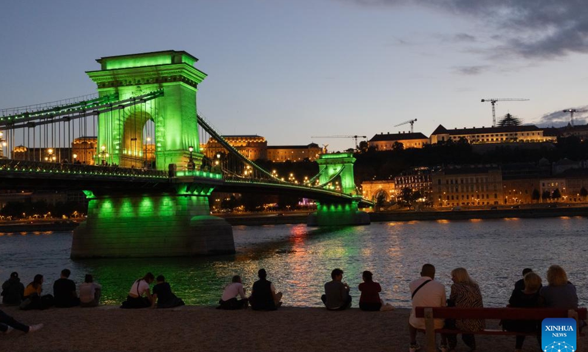 People enjoy the night view by Budapest's landmark Chain Bridge during the Chain Bridge Festival celebrating Budapest's 150th birthday in Budapest, Hungary on Sept. 16, 2023. In 1873, Buda, Pest and Obuda were unified into one single city, naming the city Budapest. (Photo by Attila Volgyi/Xinhua)

