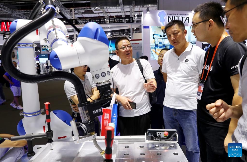 Visitors and staff members talk beside a battery box welding system during the 23rd China International Industry Fair (CIIF) in east China's Shanghai, Sept. 19, 2023. The 23rd CIIF kicked off here on Tuesday, with the theme of Digital Economy & Industrial Decarbonization.(Photo: Xinhua)