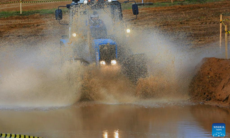 This photo taken on Oct. 14, 2023 shows a competitor driving a tractor during a tractor show in Minsk, Belarus. Belarusian tractor industry celebrated its 70th anniversary on Saturday with a tractor show held at the Great Stone China-Belarus Industrial Park in Minsk. (Photo by Henadz Zhinkov/Xinhua)