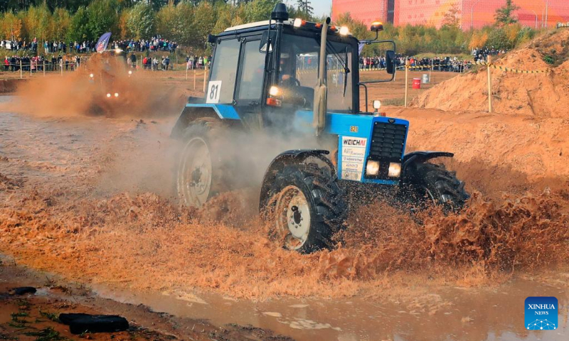 This photo taken on Oct. 14, 2023 shows a competitor driving a tractor during a tractor show in Minsk, Belarus. Belarusian tractor industry celebrated its 70th anniversary on Saturday with a tractor show held at the Great Stone China-Belarus Industrial Park in Minsk. (Photo by Henadz Zhinkov/Xinhua)