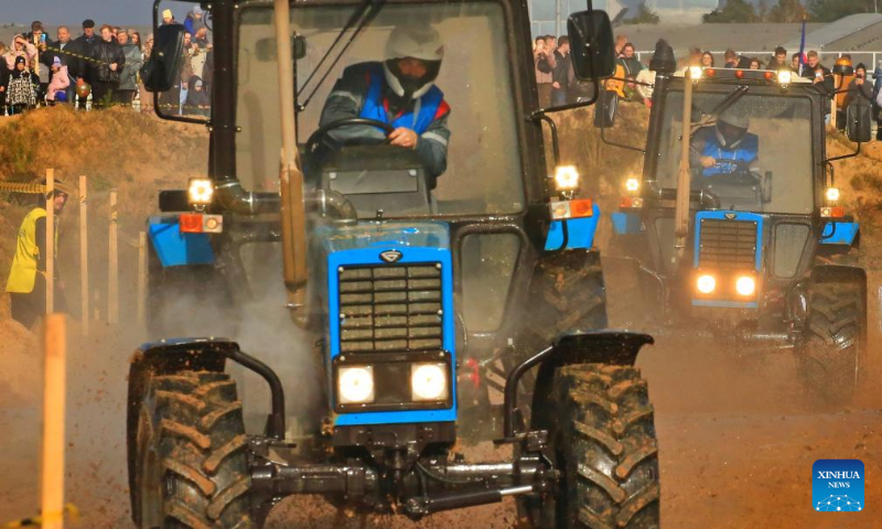 This photo taken on Oct. 14, 2023 shows competitors driving tractors during a tractor show in Minsk, Belarus. Belarusian tractor industry celebrated its 70th anniversary on Saturday with a tractor show held at the Great Stone China-Belarus Industrial Park in Minsk. (Photo by Henadz Zhinkov/Xinhua)