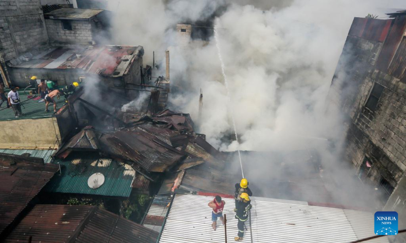 Firefighters try to put out a fire at a residential area in Quezon City, the Philippines on Oct. 15, 2023. (Xinhua/Rouelle Umali)