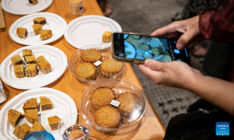 A woman takes photos of mooncakes during a Mid-Autumn Festival themed event at the China Cultural Center in Tel Aviv, Israel, Sept. 27, 2023. Various celebrations are held across the world with the approaching of Mid-Autumn Festival. (Xinhua/Chen Junqing)