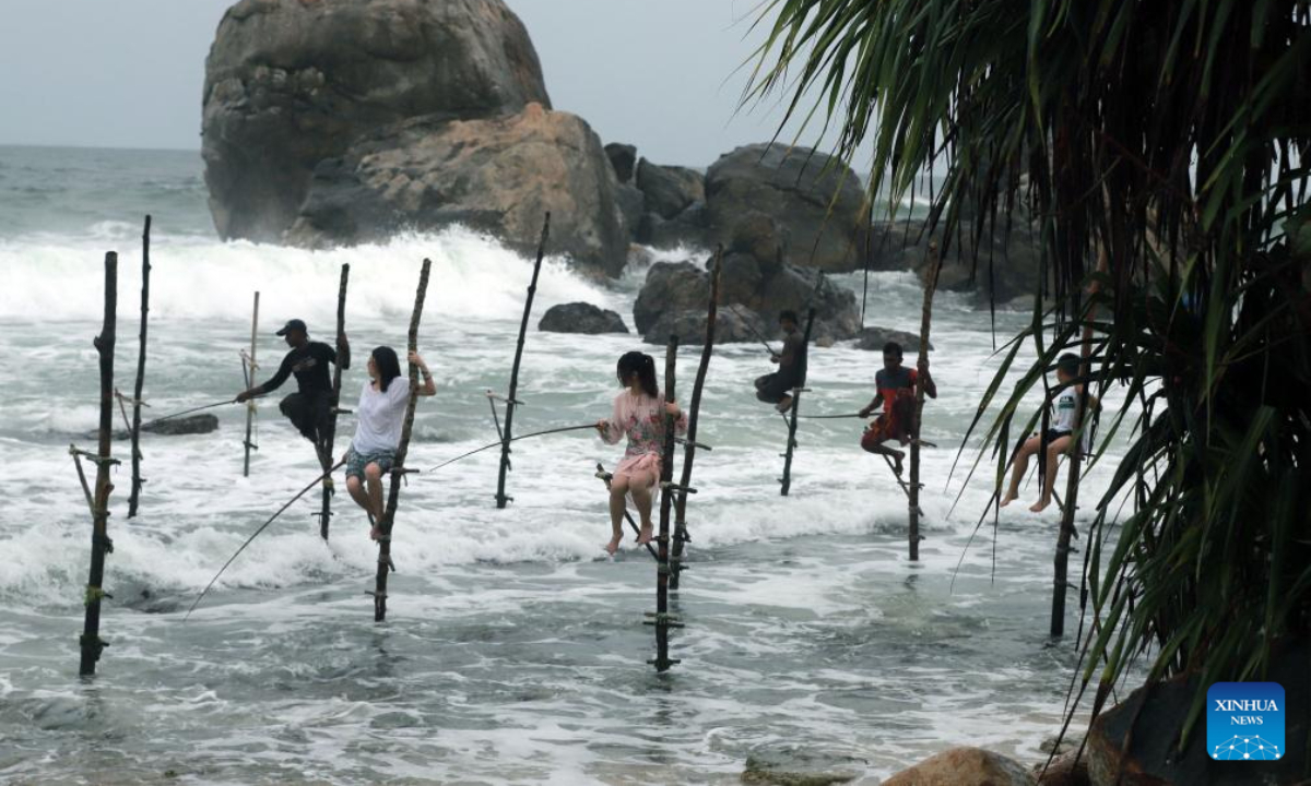 Tourists try stilt fishing in Galle, Sri Lanka, Oct 3, 2023. Photo:Xinhua