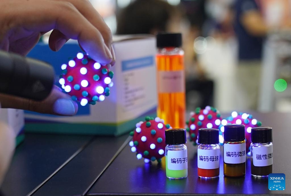 A staff member uses models to introduce a multi-index detection technology of new coding liquid chips at the stand of Shanghai Jiaotong University at the 23rd China International Industry Fair in Shanghai, east China, Sept. 19, 2023. More than 800 projects from over 80 universities are displayed at the exhibition area of universities at the ongoing 23rd China International Industry Fair.(Photo: Xinhua)