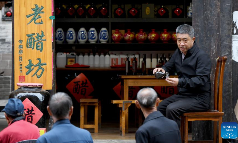 Zhang Hailong invites tourists to taste his vinegar products in the Qikou ancient town of Linxian County, north China's Shanxi Province, Sept. 26, 2023. Zhang once worked as a truck driver and opened a vinegar shop in the Qikou ancient town in 2018. Qikou, an ancient riverine town along the Yellow River, was an important trade ferry in history. However, with the development of land transportation, the Qikou ancient town declined in terms of trade volume, leaving many of its historical buildings in disrepair. In recent years, local authorities have carried out protection and restoration of historical buildings and ancient dwellings in the Qikou ancient town. At the same time, the integrated development of culture and tourism is also promoted. Today the ancient town has become a popular tourist attraction. More than 5,000 people out of a population of about 30,000 in the town are engaged in the tourism industry.（Photo：Xinhua）