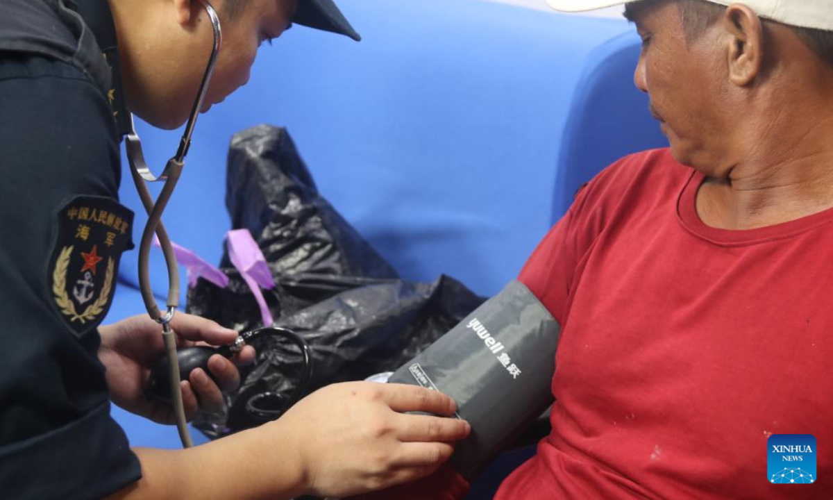 A medic of the Chinese People's Liberation Army (PLA) naval vessel Aba measures the blood pressure for a wounded Philippine fisherman on board the vessel. Photo:Xinhua