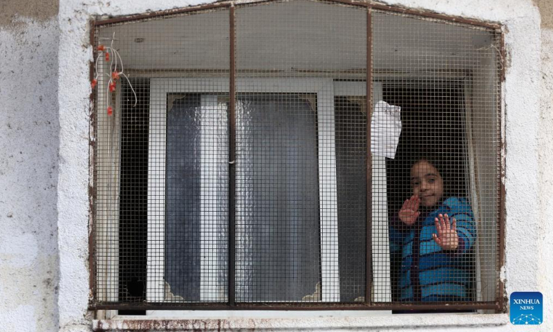 A Palestinian refugee girl looks out from her house window at Balata refugee camp in the West Bank city of Nablus, March 16, 2022. Photo: VCG