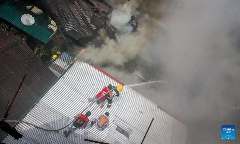 Firefighters and residents try to put out a fire at a residential area in Quezon City, the Philippines on Oct. 15, 2023. (Xinhua/Rouelle Umali)