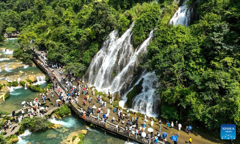 This aerial photo taken on Oct. 1, 2023 shows tourists visiting Xiaoqikong scenic spot in Libo County, southwest China's Guizhou Province. People across the country enjoy themselves in various way on the first day of the National Day holiday. (Photo by Yuan Fuhong/Xinhua)