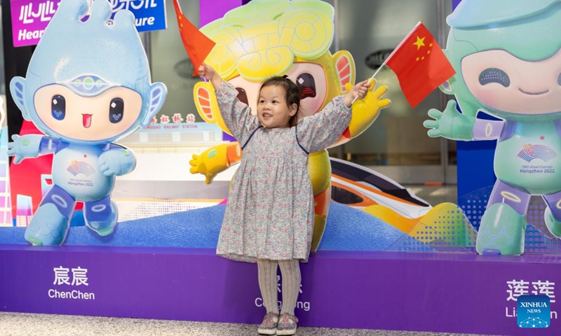 A girl waves Chinese national flags at Hongqiao railway station in Shanghai, east China, Oct. 1, 2023. People across the country enjoy themselves in various way on the first day of the National Day holiday. (Xinhua/Wang Xiang)