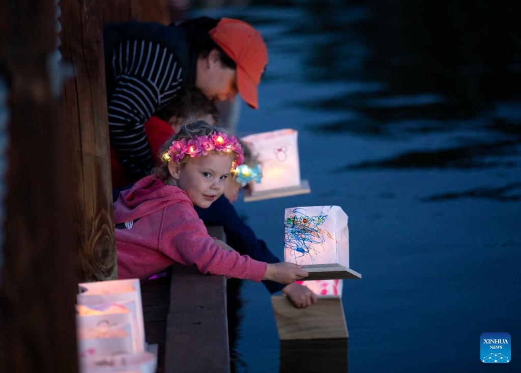 A girl sets afloat a lantern on water during the water lantern festival held in Foster City in California, the United States, Oct. 8, 2023.(Photo: Xinhua)