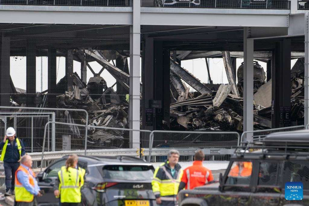 Fire crew members inspect the damage caused by a fire at the London Luton Airport's Terminal Car Park 2 in Britain, Oct. 11, 2023. All flights at London Luton Airport have been suspended until Wednesday afternoon after a massive blaze ripped through one of its car parks.(Photo: Xinhua)