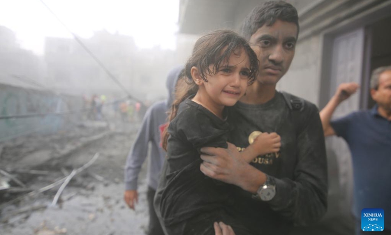 A man holds a girl in his arms and evacuates from a building destroyed in Israeli airstrikes in the southern Gaza Strip city of Rafah, on Oct. 12, 2023. The death toll of the Palestinians from the ongoing Israeli strikes on Gaza hit 1,417, while another 6,268 were wounded, according to the Gaza-based health ministry. (Photo: Xinhua)