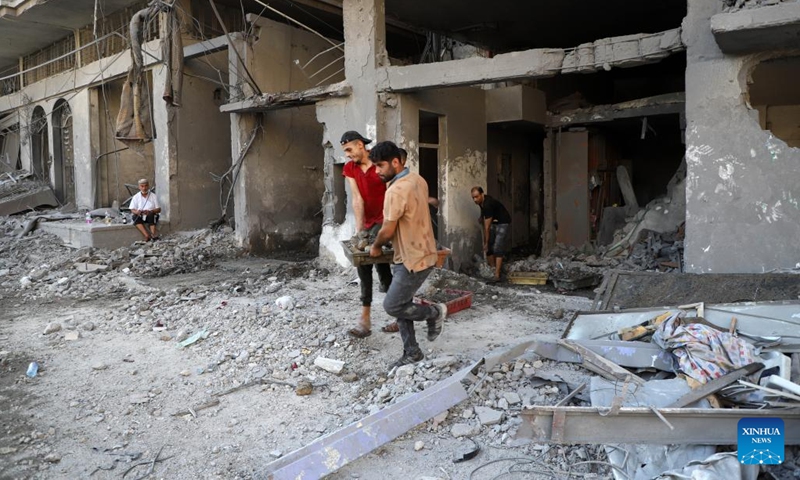 People remove rubbles of a building destroyed in an Israeli airstrike at Al-Shati refugee camp in Gaza City, on Oct. 12, 2023. The death toll of the Palestinians from the ongoing Israeli strikes on Gaza hit 1,417, while another 6,268 were wounded, according to the Gaza-based health ministry. (Photo: Xinhua)