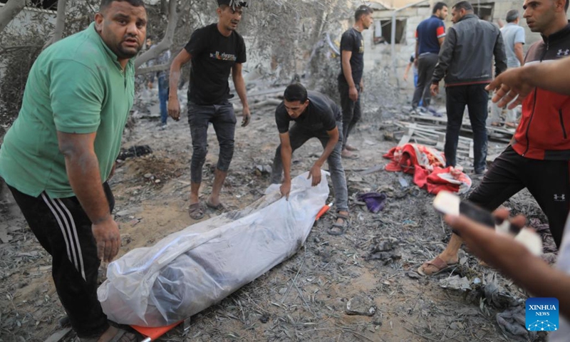 People remove the body of a victim from a building destroyed in Israeli airstrikes in the southern Gaza Strip city of Khan Younis, on Oct. 12, 2023. The death toll of the Palestinians from the ongoing Israeli strikes on Gaza hit 1,417, while another 6,268 were wounded, according to the Gaza-based health ministry. (Photo: Xinhua)