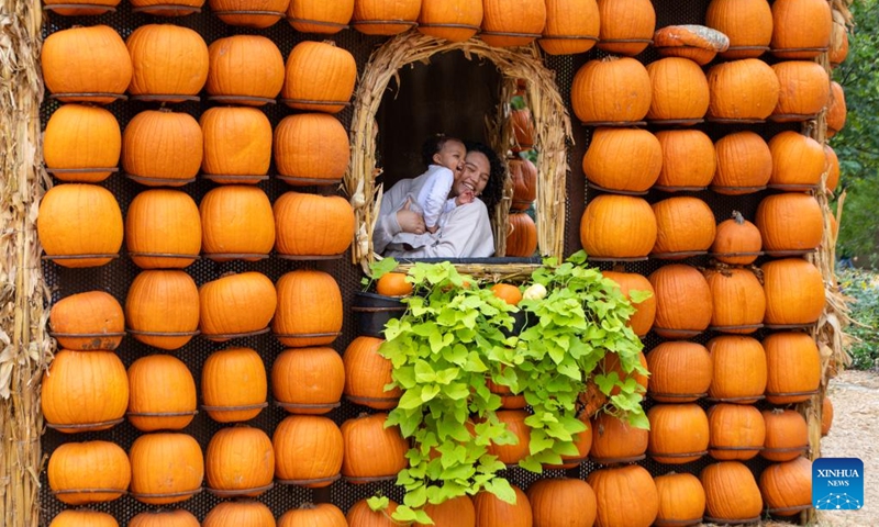 A woman holding a baby is seen inside a pumpkin house in Dallas Arboretum's Pumpkin Village, Texas, the United States, on Oct. 12, 2023. The nationally-acclaimed Pumpkin Village at Dallas Arboretum features pumpkin houses and creative displays fashioned from more than 100,000 pumpkins, gourds and squash. (Photo:Xinhua)