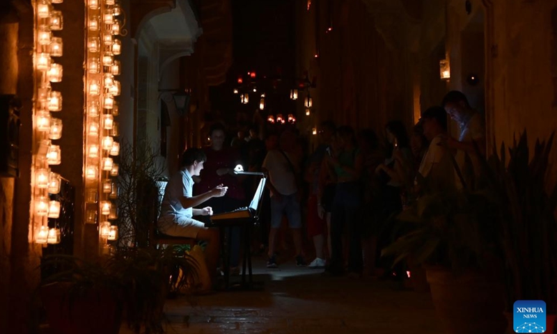 A man plays music during a candlelight festival in Birgu, Malta, Oct. 14, 2023. The candlelight festival was held here on Friday and Saturday. The candlelight illuminated Birgu's winding and narrow medieval streets. Many residents in Birgu lit up their homes and balconies with candles and opened their doors to visitors. (Photo:Xinhua)