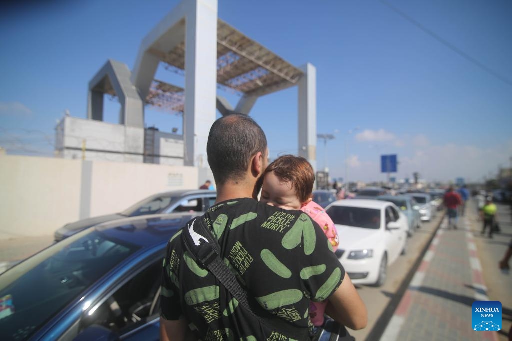 A man holding a baby waits for the opening of the Rafah border crossing in the southern Gaza Strip city of Rafah, on Oct. 16, 2023. The Gaza-ruling Palestinian Islamic Resistance Movement (Hamas) on Monday denied reports that it had agreed to a temporary ceasefire with Israel in the Gaza Strip.(Photo: Xinhua)