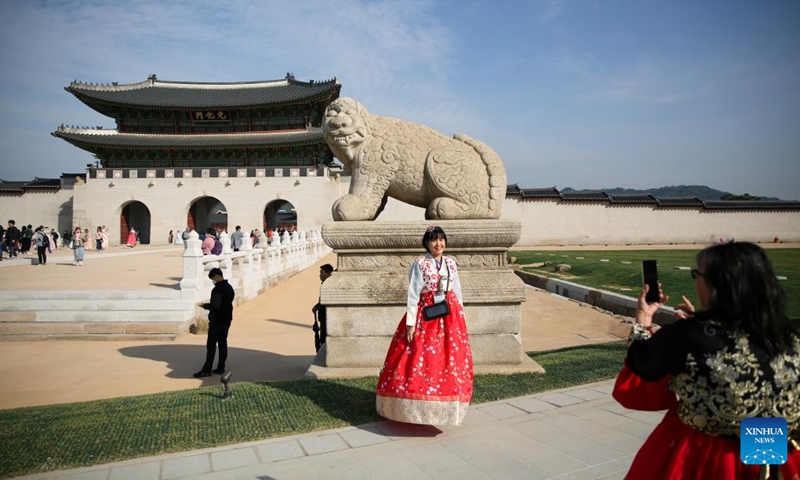 A tourist poses for a photo in front of Gwanghwamun, the largest gate of Gyeongbokgung Palace in Seoul, South Korea, Oct. 18, 2023. Gyeongbokgung Palace's Gwanghwamun gate has opened to the public after being restored to its original state for the first time.(Photo: Xinhua)