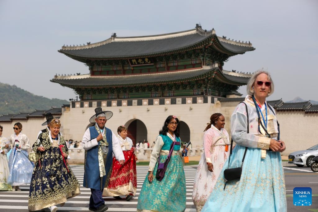 Tourists wearing Hanbok cross a street near Gwanghwamun, the largest gate of Gyeongbokgung Palace in Seoul, South Korea, Oct. 18, 2023. Gyeongbokgung Palace's Gwanghwamun gate has opened to the public after being restored to its original state for the first time.(Photo: Xinhua)