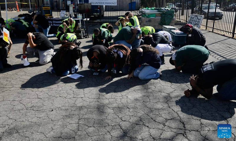 People do a Drop, Cover, and Hold On earthquake drill at the L.A. Regional Food Bank in Los Angeles, California, the United States, on Oct. 19, 2023. An annual earthquake drill was held across the United States on Thursday, in an aim to help people better protect themselves during earthquakes.(Photo: Xinhua)