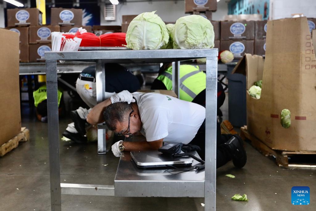 People do a Drop, Cover, and Hold On earthquake drill at the L.A. Regional Food Bank in Los Angeles, California, the United States, on Oct. 19, 2023. An annual earthquake drill was held across the United States on Thursday, in an aim to help people better protect themselves during earthquakes.(Photo: Xinhua)