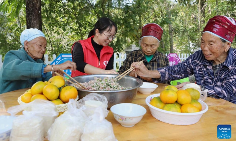 A volunteer and elders make dumplings at a Chongyang Festival activity in Gaobei Village of Ganxi Township in Shibing County, Qiandongnan Miao and Dong Autonomous Prefecture, southwest China's Guizhou Province, Oct. 22, 2023. The Chongyang Festival, also known as the Double Ninth Festival, is an annual festival to show respect and care for the elderly throughout China. The festival falls on the ninth day of the ninth Chinese lunar month, which is October 23 this year. (Photo: Xinhua)