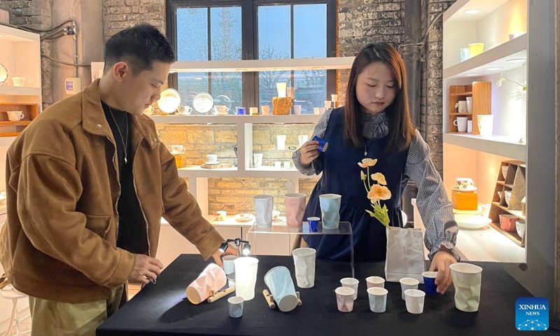 Hu Xiaoyun and her husband arrange her creations at a stand in Jingdezhen, east China's Jiangxi Province, Oct. 12, 2023. (Photo: Xinhua)