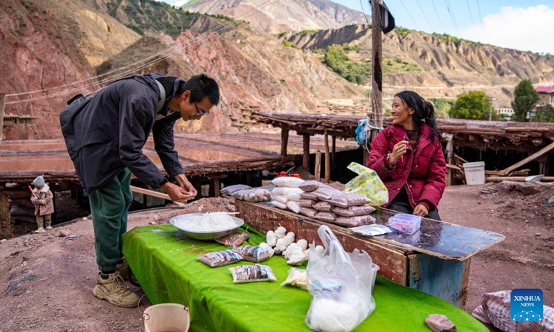 A villager promotes salt produced by her family to a tourist near a salt field in Naxi Ethnic Township of Markam County in the city of Qamdo, southwest China's Tibet Autonomous Region, Oct. 20, 2023. (Photo: Xinhua)