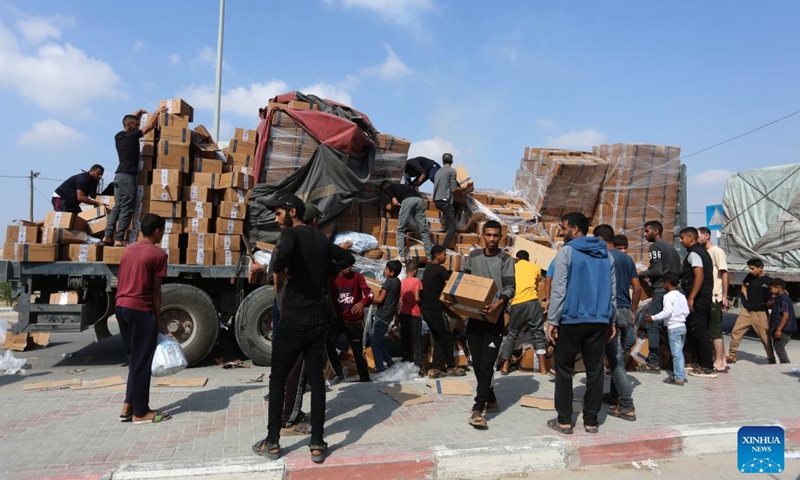 People unload humanitarian aid from a truck at the Rafah crossing in the southern Gaza Strip, on Nov. 2, 2023. A convoy of 73 trucks carrying humanitarian aid supplies is entering the besieged Gaza Strip, and hundreds of more evacuees are expected to arrive in Egypt via the Rafah border crossing on Thursday, an Egyptian source told Xinhua on the condition of anonymity.(Photo: Xinhua)