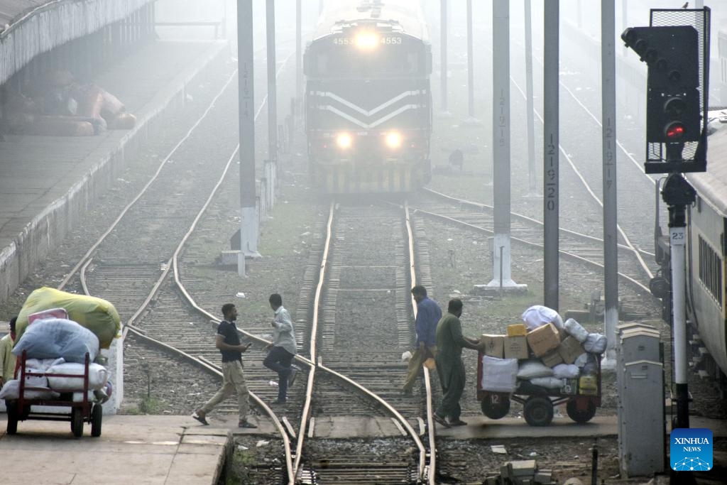 People cross railway track as a train arrives during smog in Lahore, Pakistan on Nov. 2, 2023. The government in Pakistan's Punjab province has imposed a smog emergency in the province, local media reported.(Photo: Xinhua)