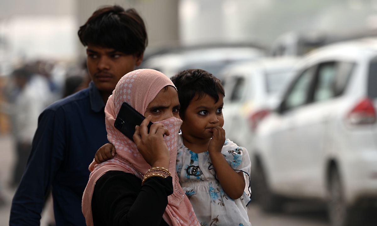 A woman carrying a baby protects her face amid heavy smog in New Delhi, India, on November 4, 2023. After New Delhi's pollution hit hazardous levels, the city has been forced to shut schools and impose emergency measures. The toxic haze once again pushed Delhi to the top of the list of the world's most polluted cities, as its air pollution spiked to 100 times the WHO's health limit. Photo: VCG 