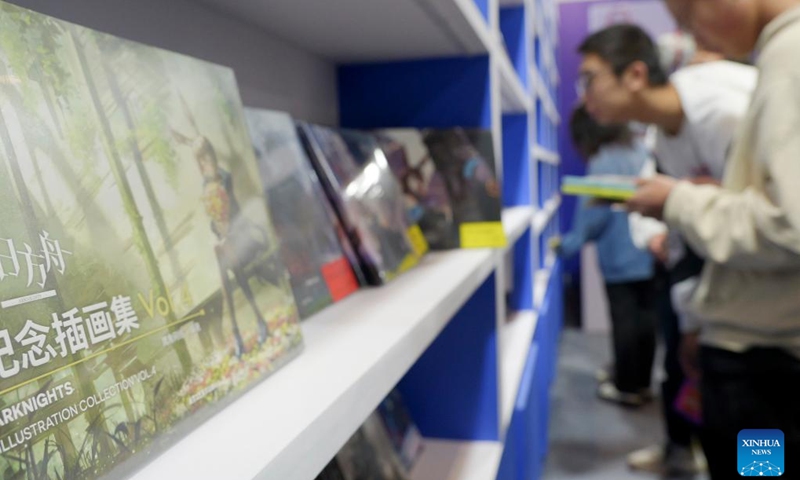 Comic enthusiasts select comic products during the 19th World Comic Conference in Anyang, central China's Henan Province, Nov. 4, 2023. The five-day 19th World Comic Conference kicked off here on Saturday with 2,931 comic works from 29 countries and regions on display. (Photo: Xinhua)