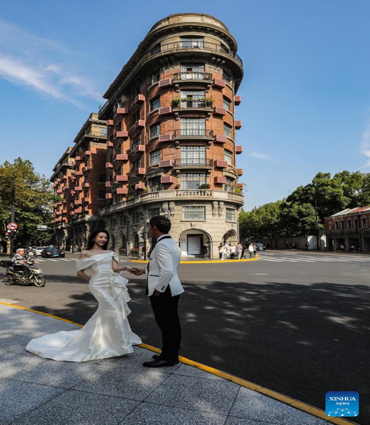 People pose for wedding photos in front of the Wukang Building in Shanghai, east China, Nov. 3, 2023. The 6th China International Import Expo (CIIE) is scheduled to be held in Shanghai from Nov. 5 to 10. The expo showcases China's new development paradigm, a platform for high-standard opening up, and a public good for the whole world. (Photo: Xinhua)