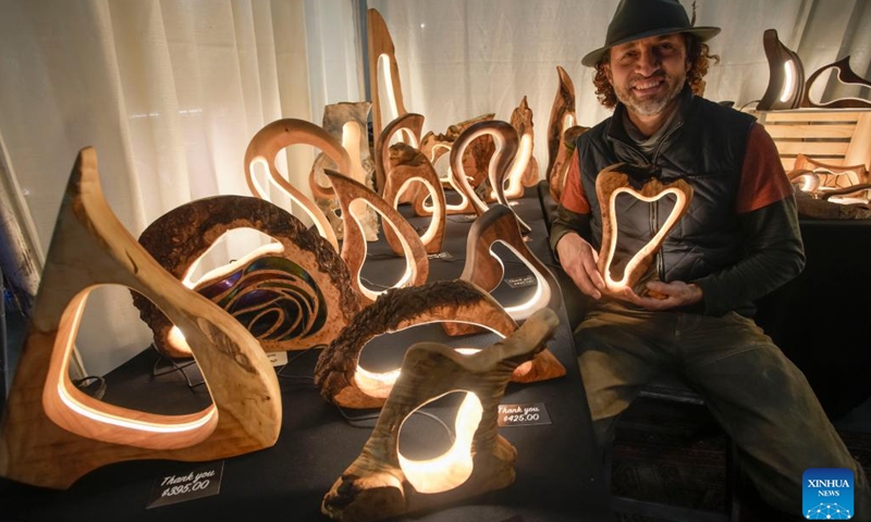 A vendor showcases his woodcraft table lamps at the Circle Craft Holiday Market in Vancouver, British Columbia, Canada, Nov. 8, 2023.(Photo: Xinhua)