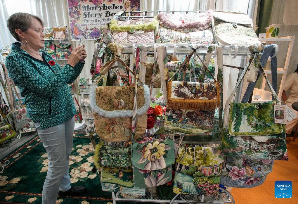 A visitor takes photos of handmade bags at the Circle Craft Holiday Market in Vancouver, British Columbia, Canada, Nov. 8, 2023.(Photo: Xinhua)