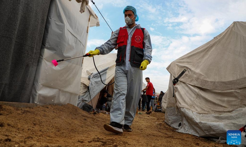 A staff worker disinfects temporary shelters in the southern Gaza Strip city of Khan Younis, on Nov. 12, 2023. (Photo: Xinhua)