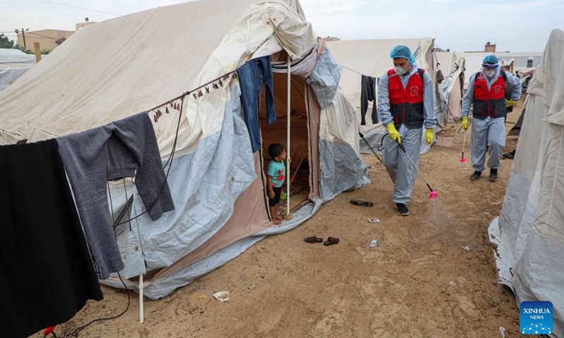 Staff workers disinfect temporary shelters in the southern Gaza Strip city of Khan Younis, on Nov. 12, 2023. (Photo: Xinhua)