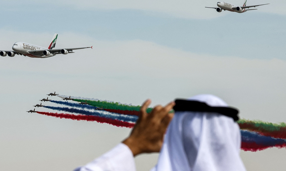 A man uses his phone to film as Aermacchi MB-339 training aircraft of the Fursan al-Emarat (UAE Knights) aerobatics team release smoke while flying past with an Emirates Airbus A380-861 and another Emirates Boeing jetliner aircraft during the 2023 Dubai Airshow at Dubai World Central International Airport in Dubai on November 13, 2023.  Photo: AFP