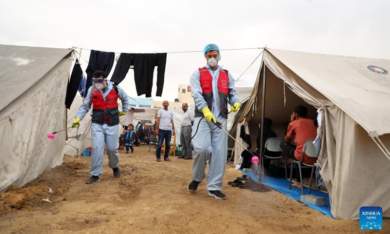 Staff workers disinfect temporary shelters in the southern Gaza Strip city of Khan Younis, on Nov. 12, 2023. (Photo: Xinhua)