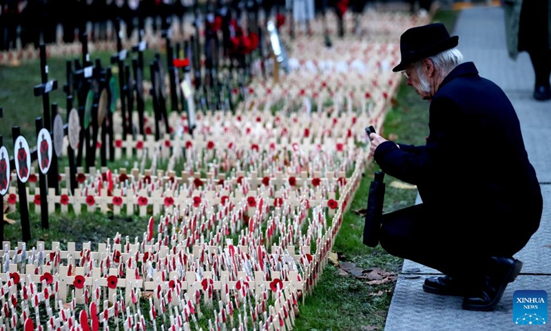 A man takes photos of poppy petals and crosses at the Field of Remembrance at Westminster Abbey on the occasion of Remembrance Sunday in London, Britain, on Nov. 12, 2023. Remembrance Sunday is an annual commemoration held on the closest Sunday to Armistice Day, Nov. 11, the anniversary of the end of the First World War.(Photo: Xinhua)